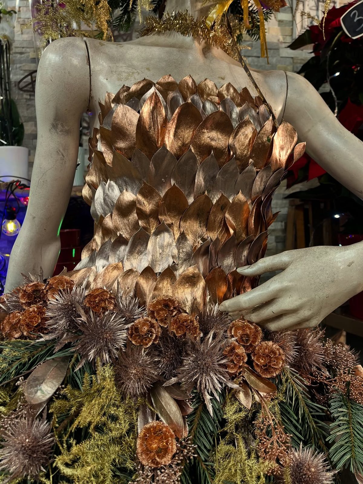 Détail d’une robe florale dorée : feuilles cuivrées, chardons et pommes de pin
