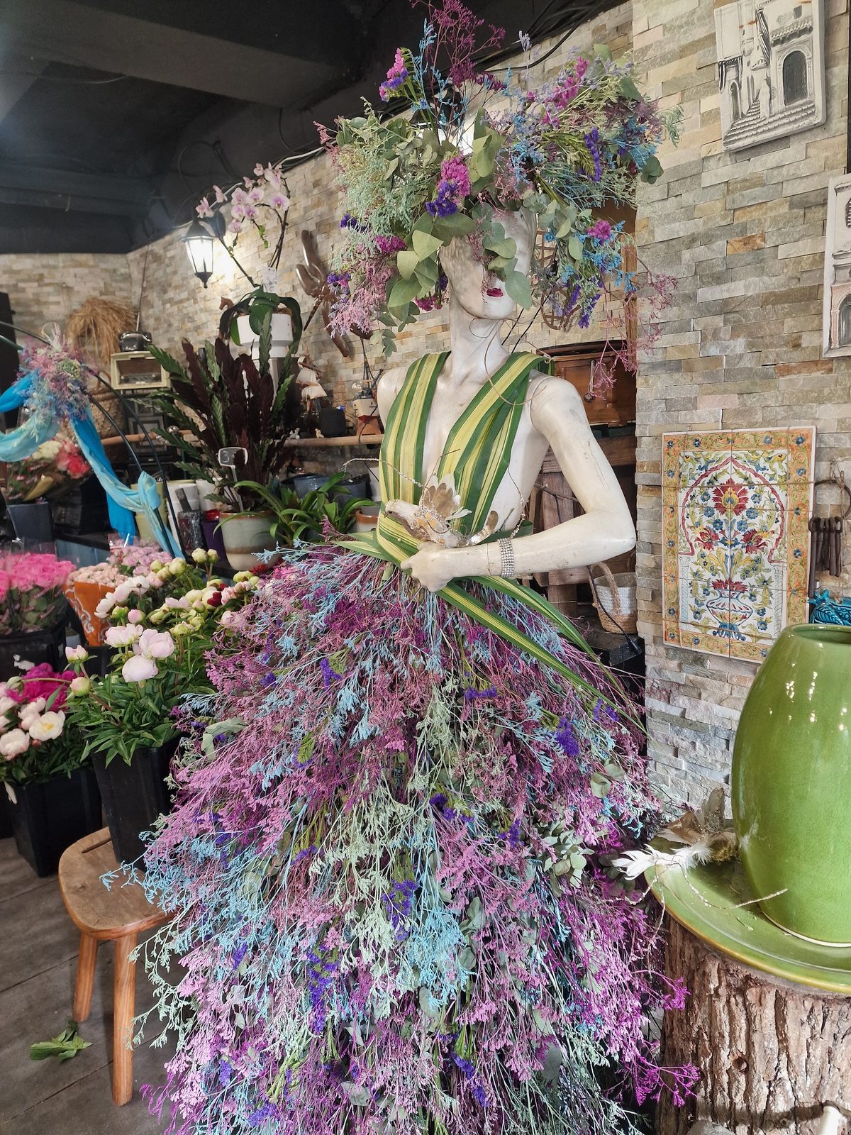 Robe florale mauve sur un mannequin, au milieu des plantes de la boutique